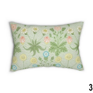 May include: A rectangular pillow with a floral pattern. The pillow features a light green background with pink, yellow, and blue flowers. The flowers are stylized and have a vintage look.