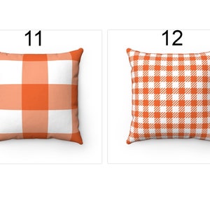 K&ouml;nnte beinhalten: Zwei quadratische Kissen mit orange-wei&szlig;em Vichy-Muster. Eines hat ein gro&szlig;es Karomuster, das andere ein kleineres Karomuster. Die Kissen werden auf wei&szlig;em Hintergrund pr&auml;sentiert. Ideal f&uuml;r die Heimdekoration.