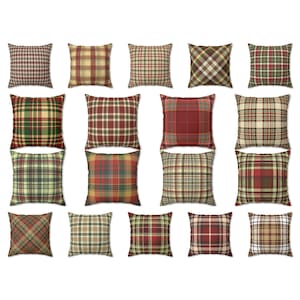 May include: A collection of square throw pillows with various plaid patterns. The pillows feature a range of colors, including red, green, brown, and gold. The plaid designs vary in size and style, offering a diverse selection for home decor.