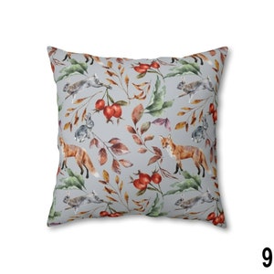 May include: Square throw pillow with a repeating pattern of foxes, rabbits, berries, and leaves in shades of orange, brown, green, and gray. The pillow has a light gray background and is a square shape.