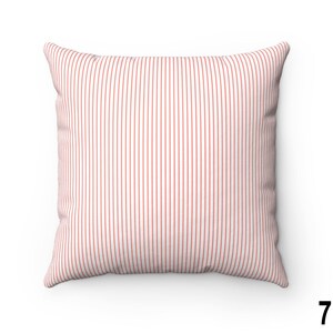 May include: A white cushion with thin red vertical stripes. The cushion is made of a soft, textured fabric.