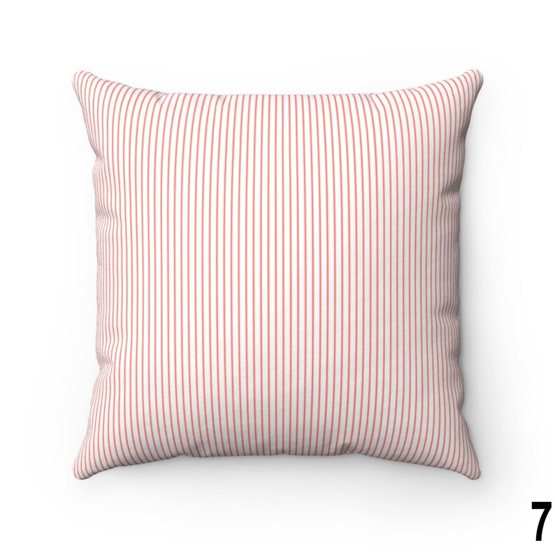 May include: A white cushion with thin red vertical stripes. The cushion is made of a soft, textured fabric.