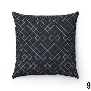 May include: A navy blue throw pillow with a geometric pattern of gold lines forming squares.