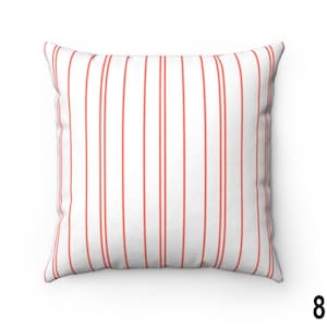 May include: A white cushion with red vertical stripes. The cushion is made from a soft, comfortable fabric and is ideal for adding a touch of colour and style to any room.