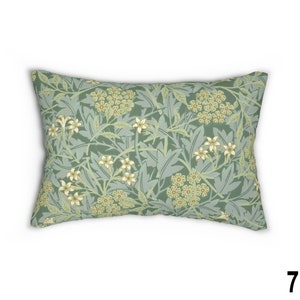 May include: A green throw pillow with a floral pattern featuring white and yellow flowers. The pillow is rectangular and has a soft, plush texture.