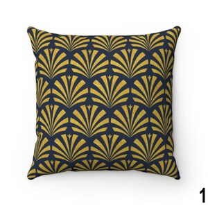 May include: A square throw pillow with a navy blue background and a gold geometric pattern of overlapping fan shapes.