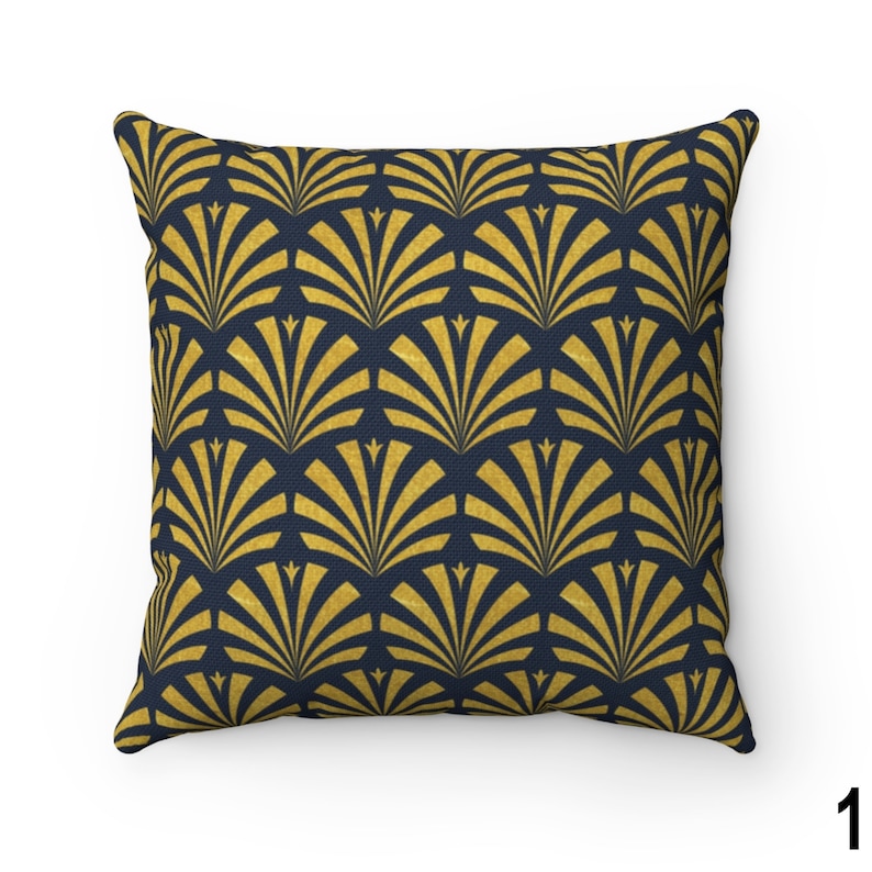 May include: A square throw pillow with a navy blue background and a gold geometric pattern of overlapping fan shapes.
