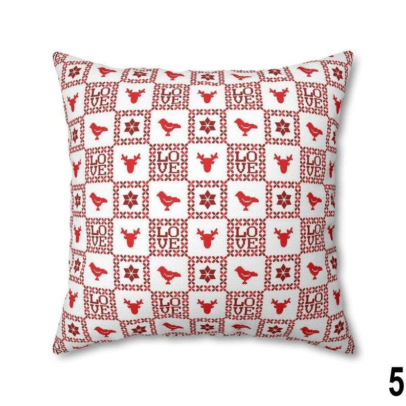 Puede incluir: Coj&iacute;n cuadrado blanco con un patr&oacute;n rojo. El patr&oacute;n incluye la palabra "LOVE", ciervos, p&aacute;jaros y dise&ntilde;os en forma de estrella. Un art&iacute;culo decorativo.