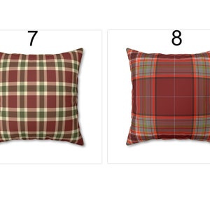 May include: Two square throw pillows with plaid patterns. One pillow features a burgundy, green, and cream plaid design. The other pillow has a burgundy, gray, and orange plaid pattern. Both pillows are displayed on a white background.