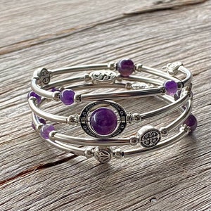 May include: A silver bracelet with multiple strands and amethyst beads. The bracelet features a large amethyst stone in a silver setting with an ornate design.