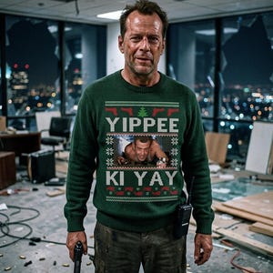 May include: A dark green long-sleeve knit jumper featuring a festive pattern with red gun silhouettes, a green Christmas tree, and the text YIPPEE KI YAY. The centre displays a photographic print of a man crawling through a ventilation shaft.
