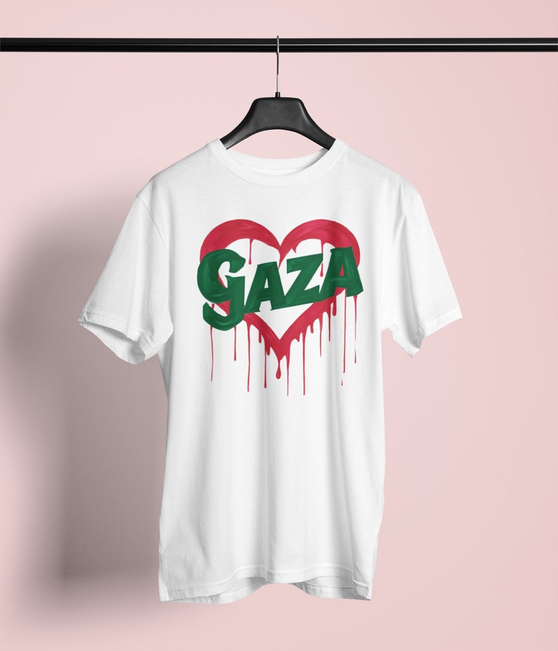 以下が含まれることがあります： 赤いハートと緑色の文字で「GAZA」と書かれた白いTシャツ。赤い塗料が垂れている。