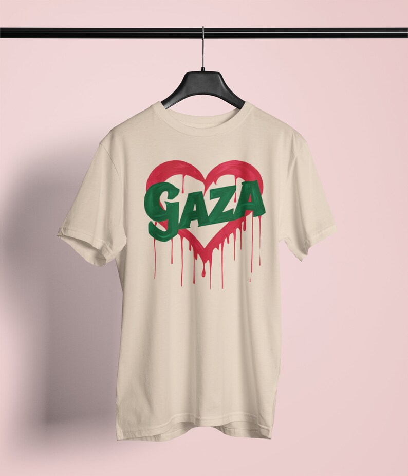 以下が含まれることがあります： ベージュのTシャツに、赤いハートの中に緑色の文字で「GAZA」と書かれている。ハートは赤い塗料が垂れている。