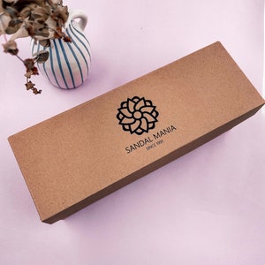 May include: A brown cardboard box with the text "SANDAL MANIA SINCE 1991" and a stylized flower logo.