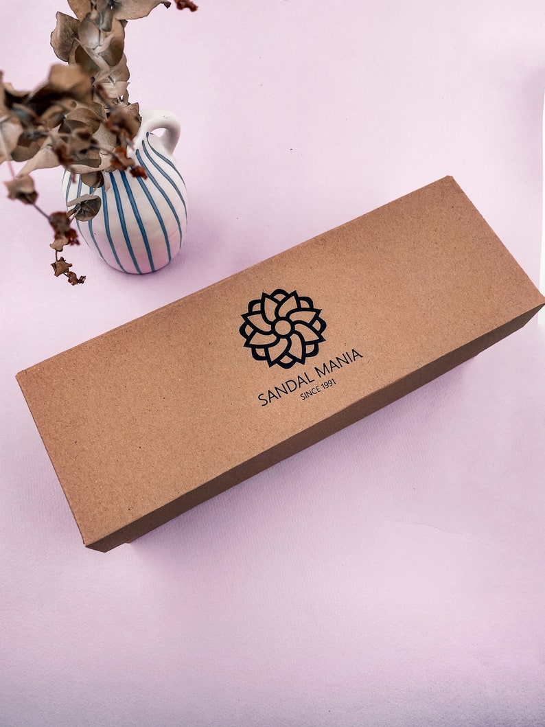May include: A brown cardboard box with the text "SANDAL MANIA SINCE 1991" and a stylized flower logo.