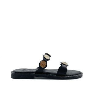 May include: Black leather sandals with gold and brown coin accents. The sandals have two straps and a flat sole.