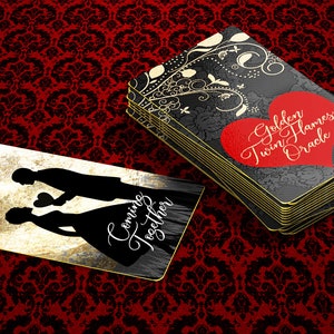May include: A deck of Golden Twin Flames Oracle cards with a red heart and gold text. The cards have a black floral design and gold edges. A single card shows silhouettes of a couple with the text "Coming Together".