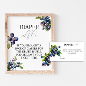 K&ouml;nnte beinhalten: Ein gerahmtes Schild und eine passende Karte f&uuml;r eine Windel-Tombola. Das Schild tr&auml;gt die Worte "Diaper Raffle" in eleganter Schrift, mit Text darunter. Aquarell-Blaubeerzweige verzieren die Ecken. Die Karte hat das gleiche Design.
