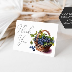 K&ouml;nnte beinhalten: Eine wei&szlig;e Karte mit den Worten "Thank You" in eleganter Schrift. Eine Aquarellillustration eines Korbes, der mit Blaubeeren und gr&uuml;nen Bl&auml;ttern &uuml;berquillt, ist abgebildet. Ein schwarzes Sechseck mit dem Text "COORDINATING ITEMS AVAILABLE LINK IN DESCRIPTION" befindet sich in der oberen rechten Ecke.