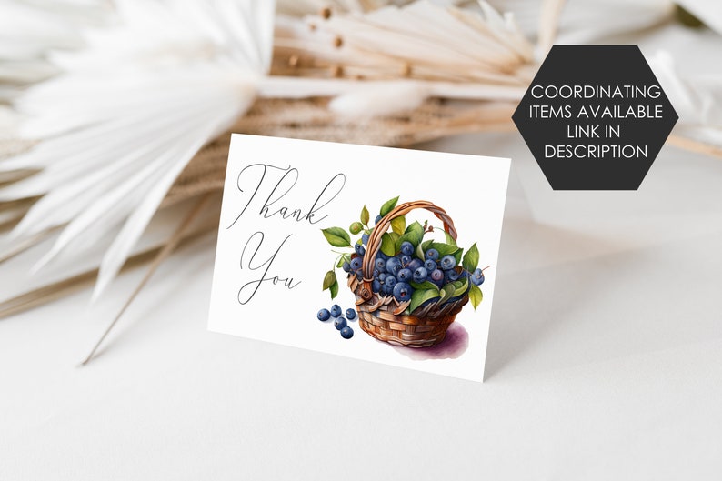K&ouml;nnte beinhalten: Eine wei&szlig;e Karte mit den Worten "Thank You" in eleganter Schrift. Eine Aquarellillustration eines Korbes, der mit Blaubeeren und gr&uuml;nen Bl&auml;ttern &uuml;berquillt, ist abgebildet. Ein schwarzes Sechseck mit dem Text "COORDINATING ITEMS AVAILABLE LINK IN DESCRIPTION" befindet sich in der oberen rechten Ecke.