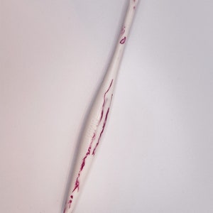 May include: White crochet hook with pink marbling. The hook is about 6 inches long.