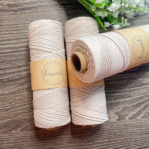 May include: Three spools of natural colored cotton rope with brown paper labels that say "brownie" in white script. The rope is a natural beige color.