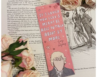 May include: A pink bookmark featuring the quote "If I loved you less, I might be able to talk about it more" and a drawing of a man. The bookmark is decorated with small flowers and hearts, and is set on an open book with pink roses.