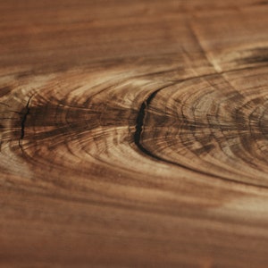 May include: Close-up of a wood grain pattern with a dark brown colour and a light brown colour. The wood grain has a natural, organic look.