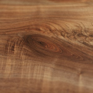 May include: Close-up of a wood grain pattern with a knot in the centre. The wood is a rich brown colour with a smooth finish.