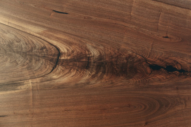 May include: Close-up of a dark brown wood grain with a knot and a natural wood finish.