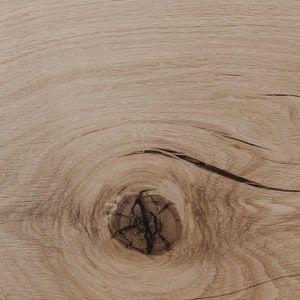 Puede incluir: Primer plano de una superficie de madera marr&oacute;n claro con un nudo en el centro. La veta de la madera es visible y tiene un aspecto natural y r&uacute;stico.