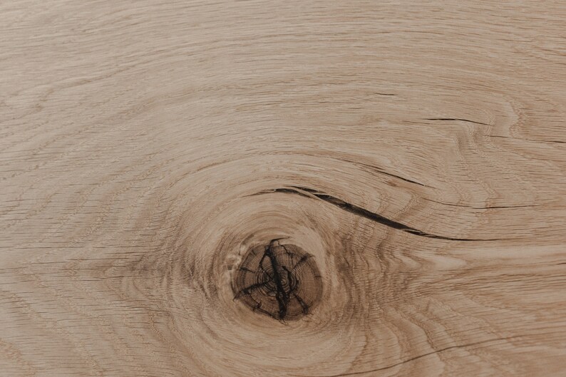 Puede incluir: Primer plano de una superficie de madera marr&oacute;n claro con un nudo en el centro. La veta de la madera es visible y tiene un aspecto natural y r&uacute;stico.