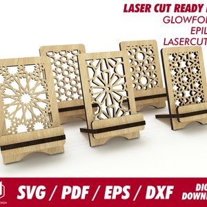 May include: Set of five laser cut wooden phone stands featuring intricate geometric designs. The stands are made from light brown wood and have a dark brown base. The designs are inspired by Islamic art and feature a variety of stars, circles, and other geometric shapes. The stands are ideal for holding phones, tablets, or other small devices.