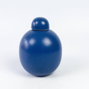 Könnte beinhalten: Eine blaue Keramikdose mit einem runden Deckel. Die Dose ist einfarbig und hat eine glatte, glänzende Oberfläche.
