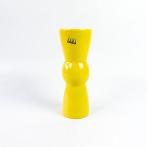 May include: A bright yellow ceramic vase with a bulbous middle section and a label that reads "ATA Keramik".