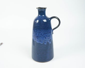 May include: A blue ceramic pitcher with a speckled glaze and a rounded handle.