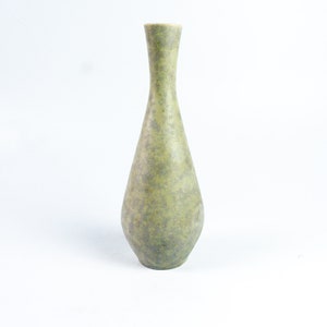 May include: A green ceramic vase with a speckled glaze. The vase has a narrow neck and a rounded body.