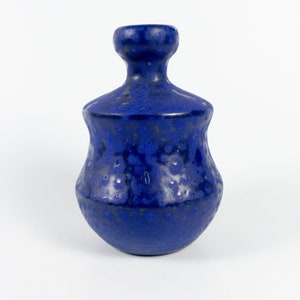 May include: A cobalt blue ceramic vase with a textured surface. The vase has a bulbous body, a narrow neck, and a flared rim. The glaze has a speckled appearance, adding visual interest to the piece.