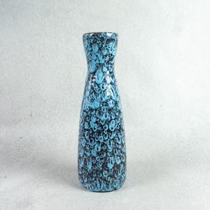 May include: A blue and black ceramic vase with a textured, patterned surface. The vase has a narrow neck and a wide base.