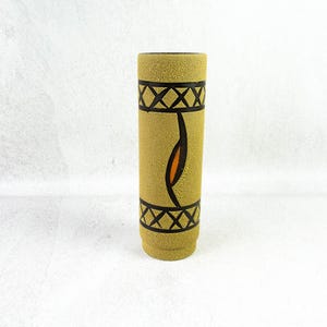 May include: A cylindrical vase with a textured, tan surface. The vase features black geometric patterns and a central design with orange and black accents. The vase is a decorative item.