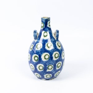 May include: A blue and white ceramic vase with green accents. The vase has a round body and two handles. It is decorated with a pattern of white circles with green rings.