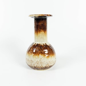 May include: A brown and white ceramic vase with a wide, round base and a narrow neck. The vase has a mottled glaze with brown and white streaks.