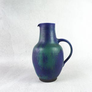 Peut inclure: Un pichet en céramique bleu et vert avec un corps arrondi et une anse. Le pichet a une finition émaillée avec un effet marbré.