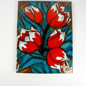 Könnte beinhalten: Eine Keramikfliese mit einem farbenfrohen Design aus roten, weißen und blauen Tulpen auf blauem und grünem Hintergrund.