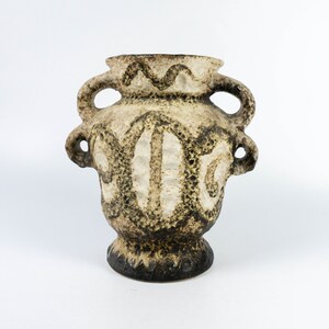 May include: A brown and white ceramic vase with two handles. The vase has a textured surface and a geometric design.
