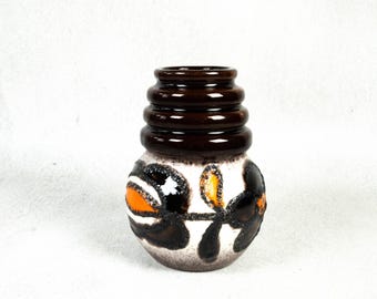 May include: A brown and white ceramic vase with a floral design. The vase has a wide base and a narrow neck. The floral design is in shades of orange, brown, and white.