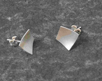 May include: A pair of silver earrings with a square shape. The earrings have a brushed finish and are made of metal.