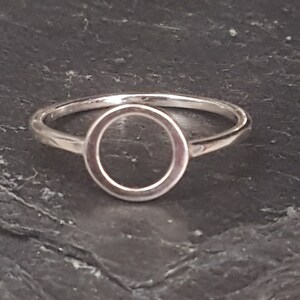 Könnte beinhalten: Ein silberner Ring mit einem Kreisdesign. Der Ring ist schlicht und elegant.