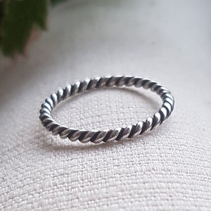 Op de afbeelding: Een zilveren ring met een gedraaide band. De ring is simpel en delicaat.