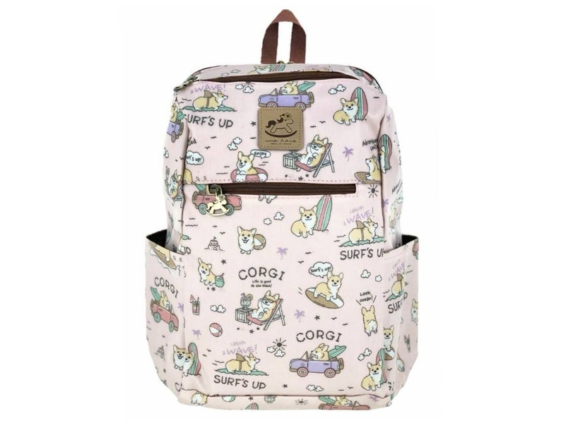 May include: Pink backpack with a cartoon corgi design. The backpack features a variety of corgis in different poses, including surfing, driving cars, and relaxing on the beach. The text "Surf's Up" and "Corgi" are repeated throughout the design.